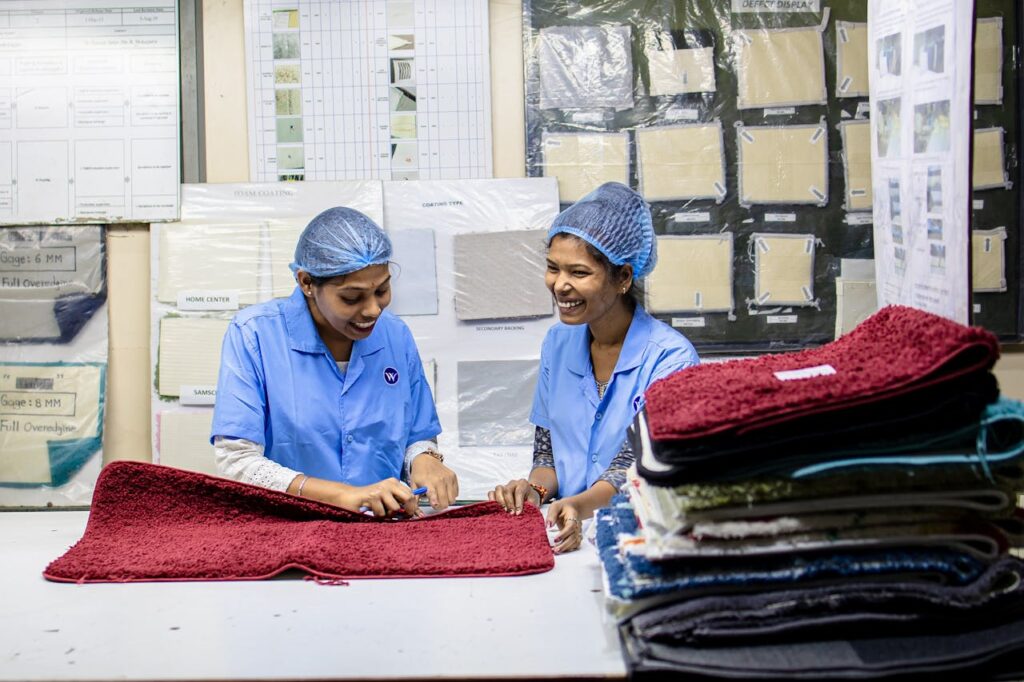 Two female textile workers inspecting fabrics with cheerful expressions in a factory setting.