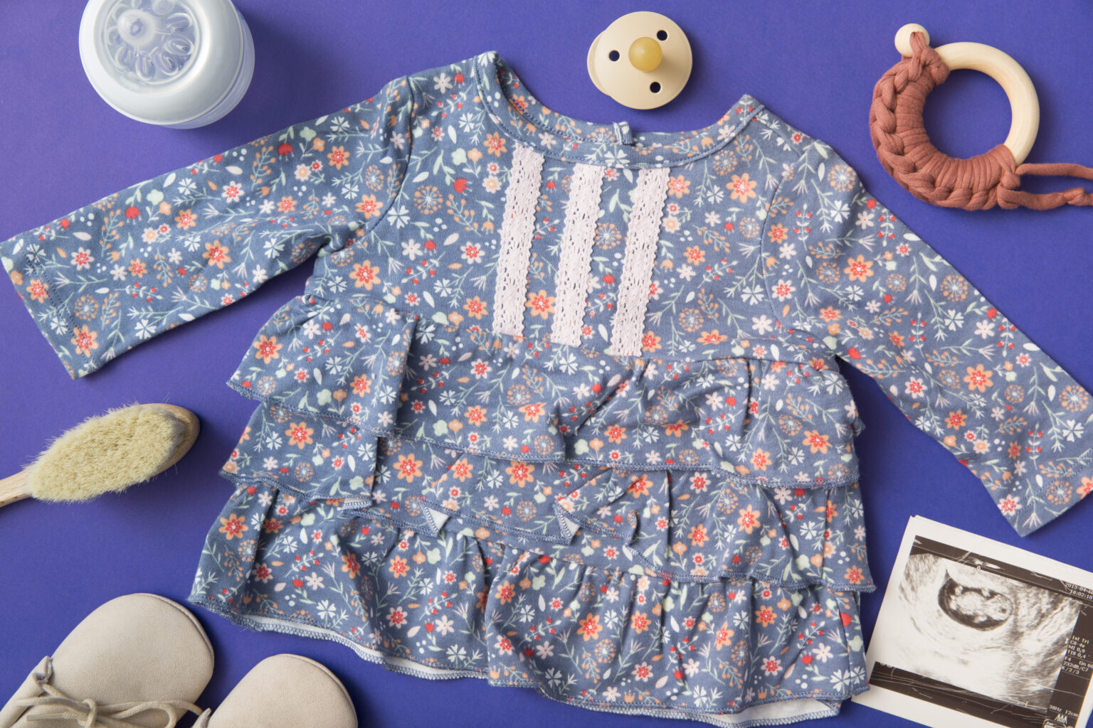 baby dress surrounded with milk bottle pacifier brush shoes ultrasound picture blue background