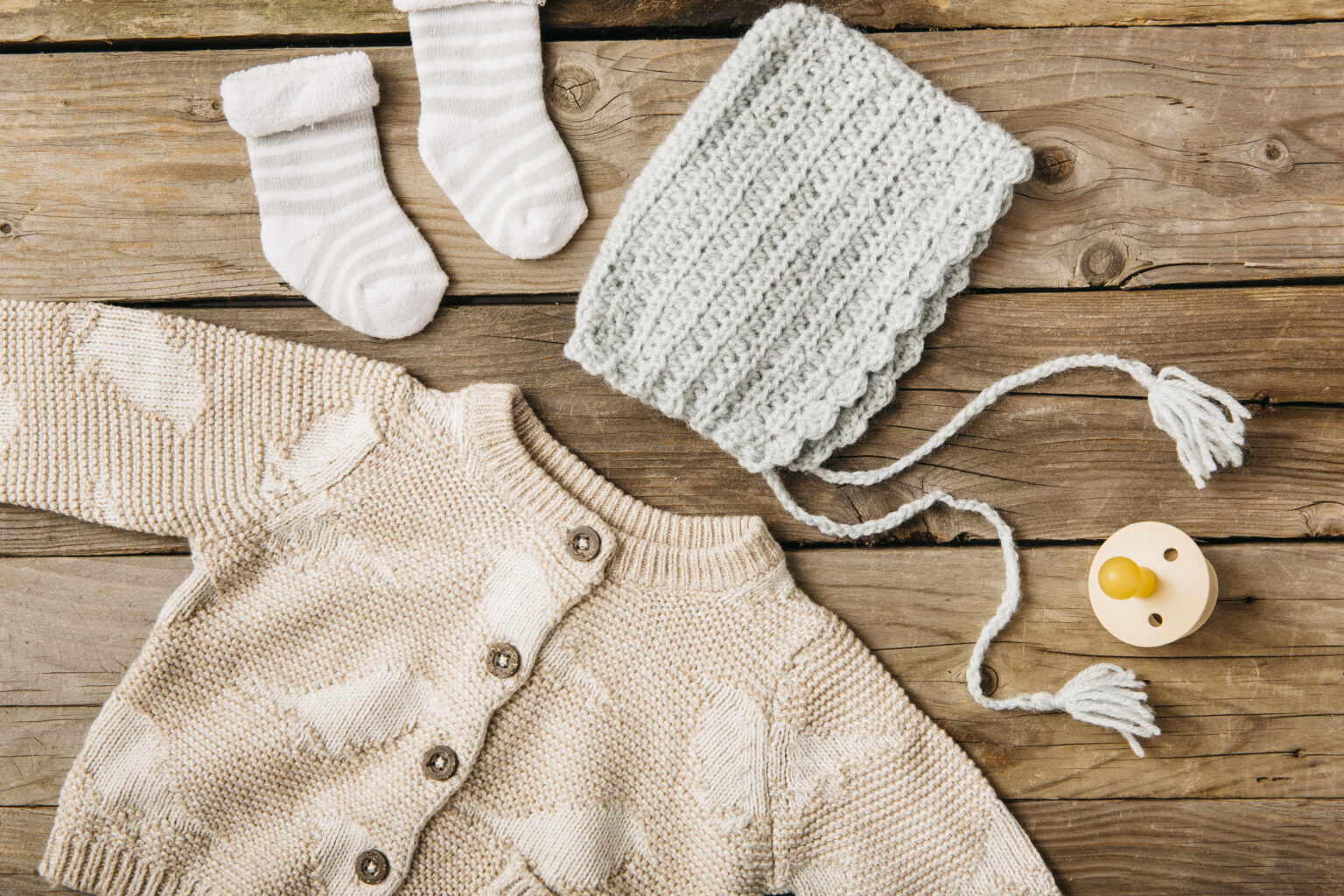overhead view woolen baby s clothing with pacifier wooden table