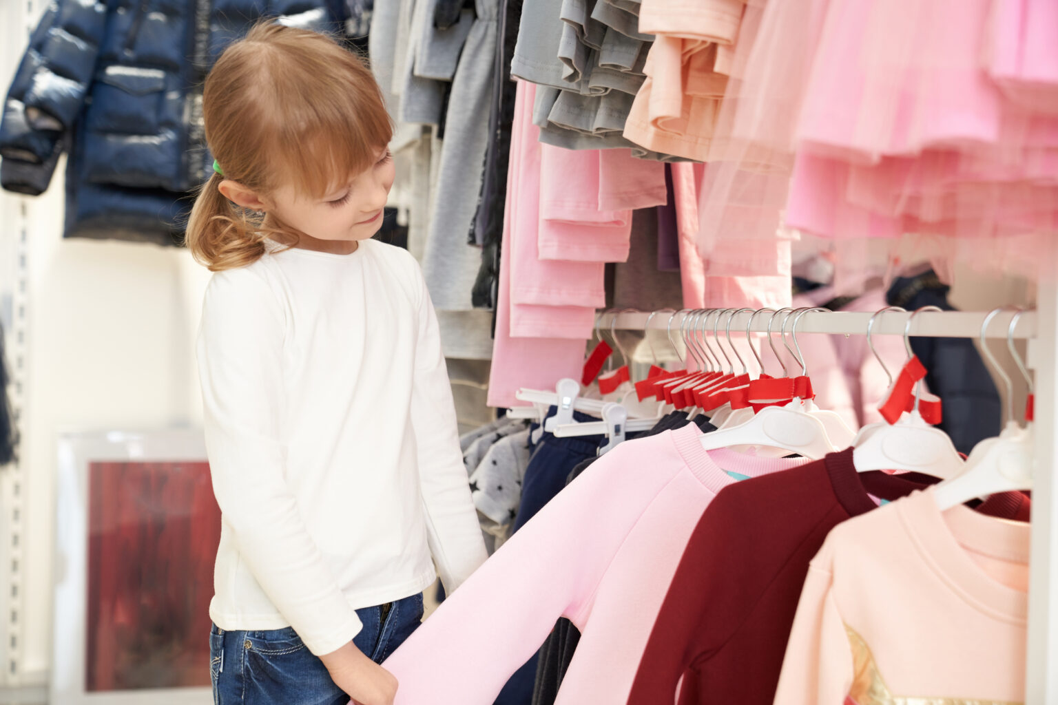 pretty child choosing clothing in store.
